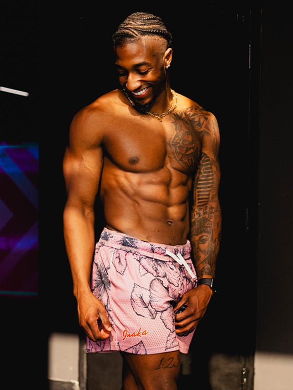Coach is smiling topless and having a pink shorts on.